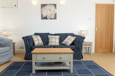 a living room with a blue couch and a table at Mulberry Cottage in Whithorn