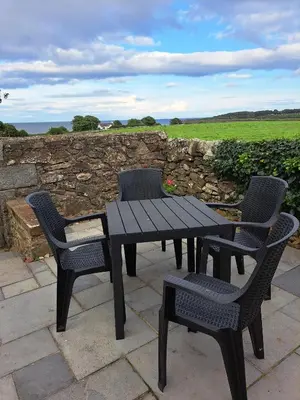 a black picnic table and chairs on a patio at Mulberry Cottage in Whithorn