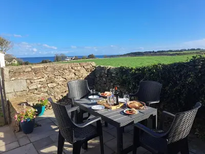 a table and chairs on a patio with a view of the ocean at Mulberry Cottage in Whithorn