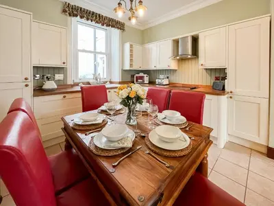 a kitchen with a wooden table and red chairs at South Haven in Portpatrick