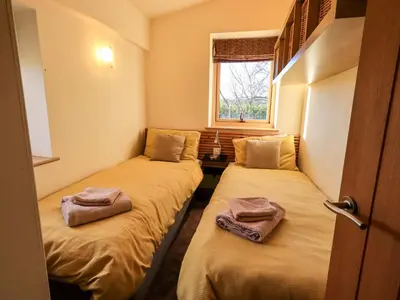 two beds in a small room with a window at Cedrus Lodge in Penrith