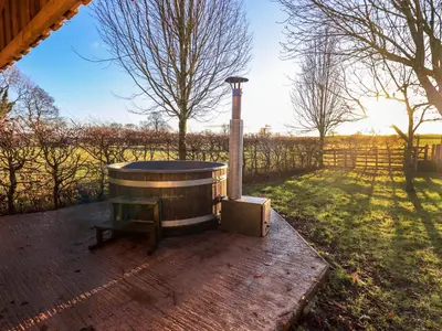 a hot tub sitting on a patio with a fence at Cedrus Lodge in Penrith