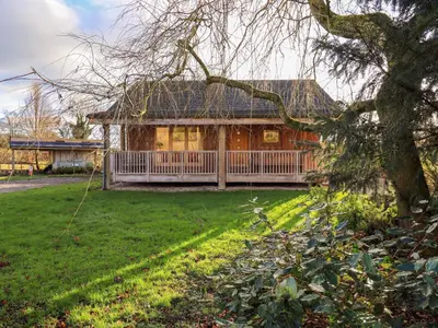 a house with a large porch on a green yard at Cedrus Lodge in Penrith