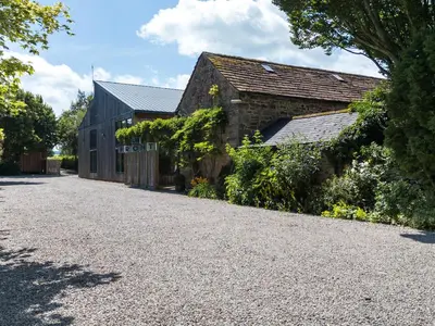 a barn with a gravel driveway next to a building at Cedrus Lodge in Penrith