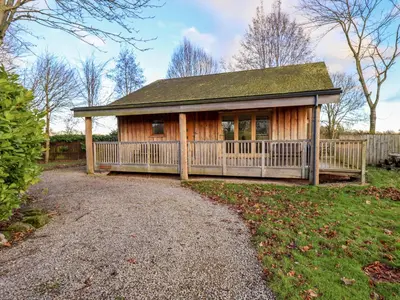 a house with a porch and a fence at Larch Lodge in Penrith