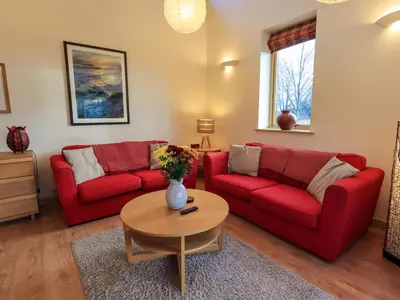 a living room with two red couches and a table at Larch Lodge in Penrith