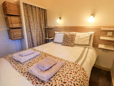 a bedroom with a bed with two towels on it at Larch Lodge in Penrith