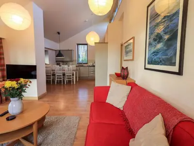 a living room with a red couch and a table at Larch Lodge in Penrith