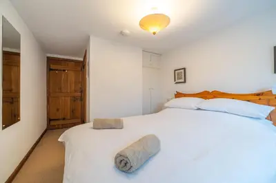 a bedroom with a large white bed with a wooden headboard at Ghyll Foot - At the foot of Place Fell, Ullswater in Patterdale