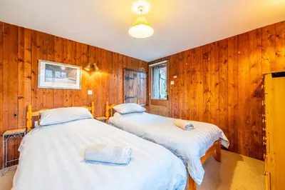 two beds in a room with wooden walls at Ghyll Foot - At the foot of Place Fell, Ullswater in Patterdale