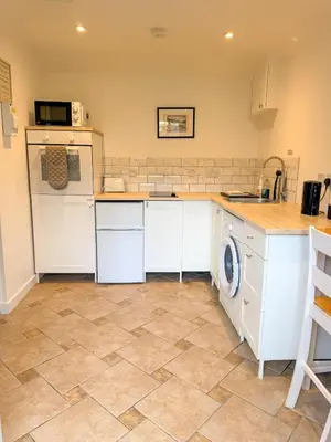 a kitchen with white cabinets and a tile floor at The Retreat, self-contained cosy Anex, M6 A75 Gretna Green in Rigg