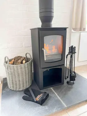 a black stove sitting in a room with a basket at The Retreat, self-contained cosy Anex, M6 A75 Gretna Green in Rigg