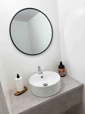 a bathroom sink with a round mirror above it at The Retreat, self-contained cosy Anex, M6 A75 Gretna Green in Rigg
