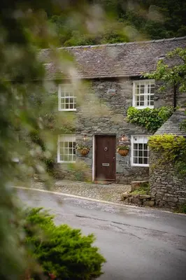 a stone house with a door and flowers on it at Grange Bridge Cottage in Grange