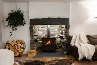 a living room with a stone fireplace and a couch at Grange Bridge Cottage in Grange