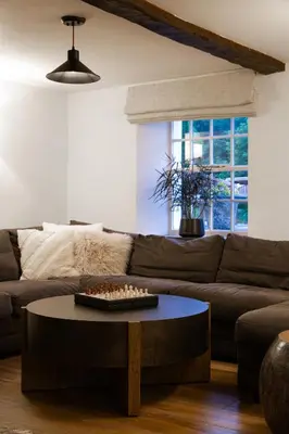 a living room with a brown couch and a table at Grange Bridge Cottage in Grange