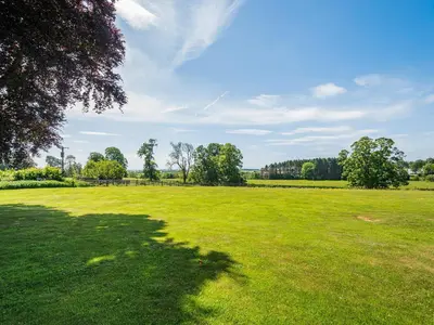 a large green field with a tree in the foreground at Mossknowe Escape in Annan
