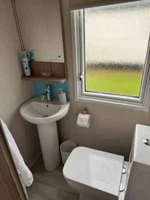 a bathroom with a sink and a toilet and a window at The Retreat - Turnberry Holiday Park Amazing Sea View in Girvan