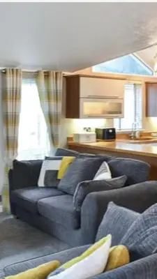 a living room with a blue couch and a kitchen at Woodland Lodge in Plumbland