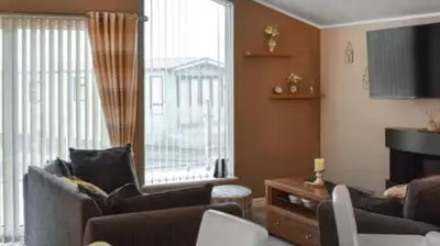 a living room with a couch and a television at Woodland Lodge in Plumbland