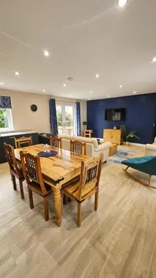 a living room with a wooden table and chairs at Cosy wee cottage -modern, open plan, parking, EV in Glencaple