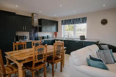 a kitchen and living room with a table and a couch at Cosy wee cottage -modern, open plan, parking, EV in Glencaple