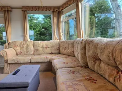 a living room with a couch and a table at Elf Wood Lodge - Swimming Spa, Sky Sports, Tennis, Hadrian's Wall listing in Port Carlisle