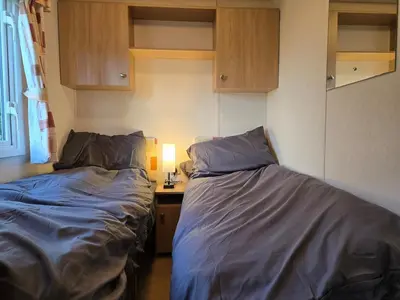 a bedroom with two beds and a desk with a lamp at Elf Wood Lodge - Swimming Spa, Sky Sports, Tennis, Hadrian's Wall listing in Port Carlisle