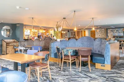 a restaurant with blue booths and tables and chairs at Elf Wood Lodge - Swimming Spa, Sky Sports, Tennis, Hadrian's Wall listing in Port Carlisle