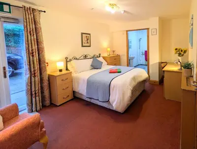 a bedroom with a large bed and a chair at Fantastic prices for stays of 4 weeks or more - ensuite double rooms -self-catering in Dumfries