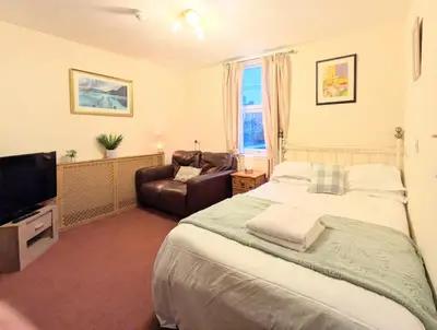 a bedroom with a bed and a couch and a television at Fantastic prices for stays of 4 weeks or more - ensuite double rooms -self-catering in Dumfries