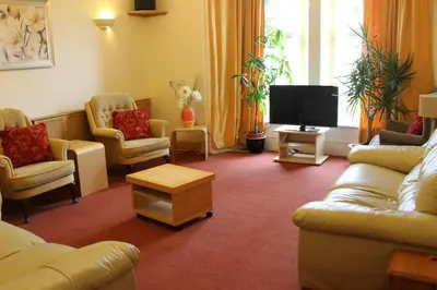 a living room with couches and a flat screen tv at Fantastic prices for stays of 4 weeks or more - ensuite double rooms -self-catering in Dumfries