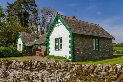 a white and green house with a stone wall at No1 Chapelton Cottage in Kirkcudbright