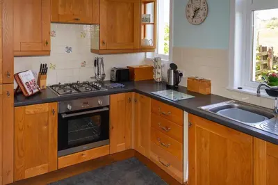 a kitchen with wooden cabinets and a stove and a sink at No1 Chapelton Cottage in Kirkcudbright