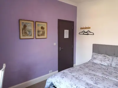 a bedroom with a bed and a purple wall at Carlisle Homestay - Double Room in Carlisle