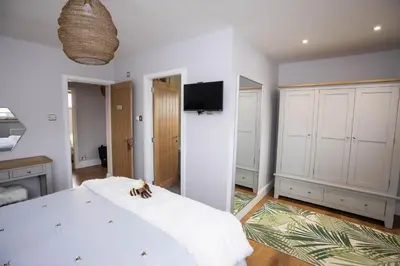 a bedroom with a large white bed and a flat screen tv at Hidden Hive in Gretna