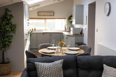 a kitchen and dining room with a table and chairs at Hidden Hive in Gretna