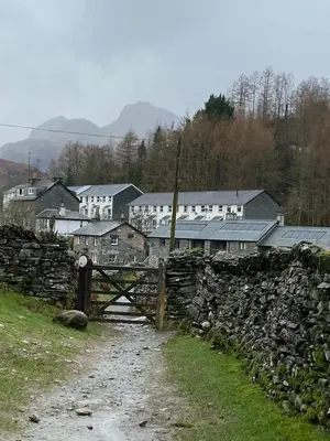 a village with a fence and a stone wall at Cosy home in centre of Lake District National Park in Chapel Stile