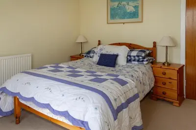 a bedroom with a bed with a blue and white comforter at Dunrod - Overlooking the bay in Kirkcudbright