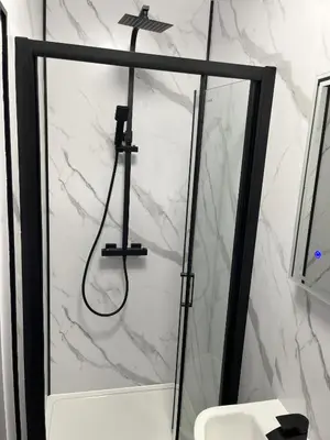 a shower in a bathroom with a white marble wall at Modern Junior Suite, Seascale, Cumbria in Seascale