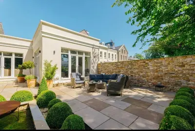 a patio with chairs and a brick wall at Mount Auldyn House - The Cottage in Ramsey
