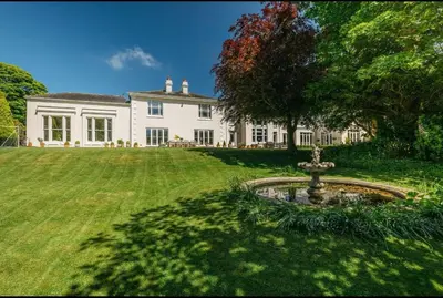 a large white house with a fountain in the yard at Mount Auldyn House - The Cottage in Ramsey