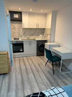 a kitchen with white cabinets and a table and a desk at private Studio with its own kitchen and bathroom in Moffat