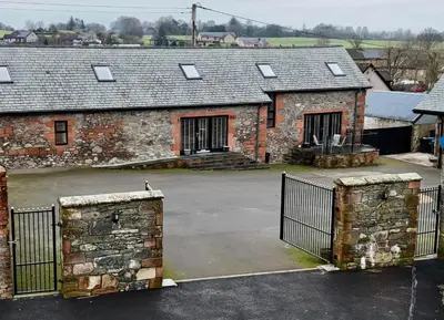 an old stone building with a gate in a parking lot at The Steading in Dumfries