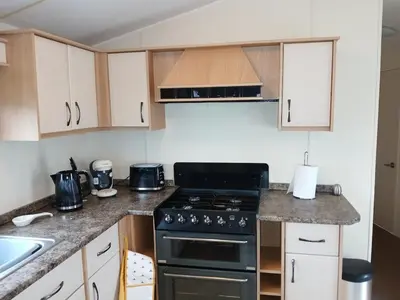 a small kitchen with a stove and a sink at Harriet's Haven - Endless Pool, Tennis, Sky TV in Port Carlisle