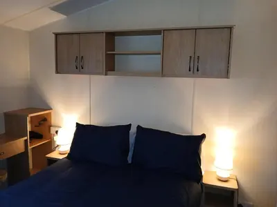 a bedroom with a blue bed with two lights on two tables at Harriet's Haven - Endless Pool, Tennis, Sky TV in Port Carlisle