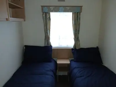 two beds in a small room with a window at Harriet's Haven - Endless Pool, Tennis, Sky TV in Port Carlisle
