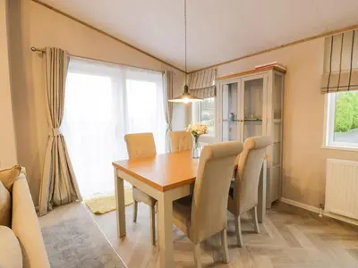 a dining room with a wooden table and chairs at Debonair Lodge in Newton Stewart