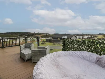 a balcony with a table and chairs on a deck at Debonair Lodge in Newton Stewart