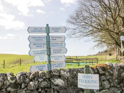 a street sign with arrows on a stone wall at Debonair Lodge in Newton Stewart